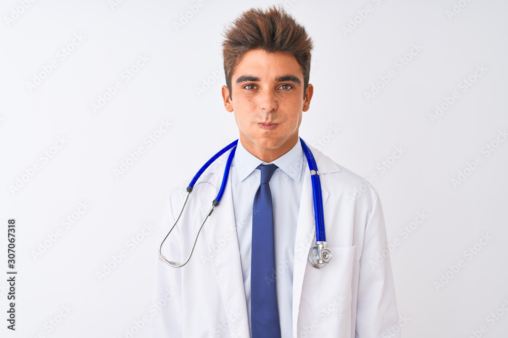 Young handsome doctor man wearing stethoscope over isolated white background puffing cheeks with funny face. Mouth inflated with air, crazy expression. Young handsome doctor man wearing stethoscope over isolated white background puffing cheeks with funny face. Mouth inflated with air, crazy expression.