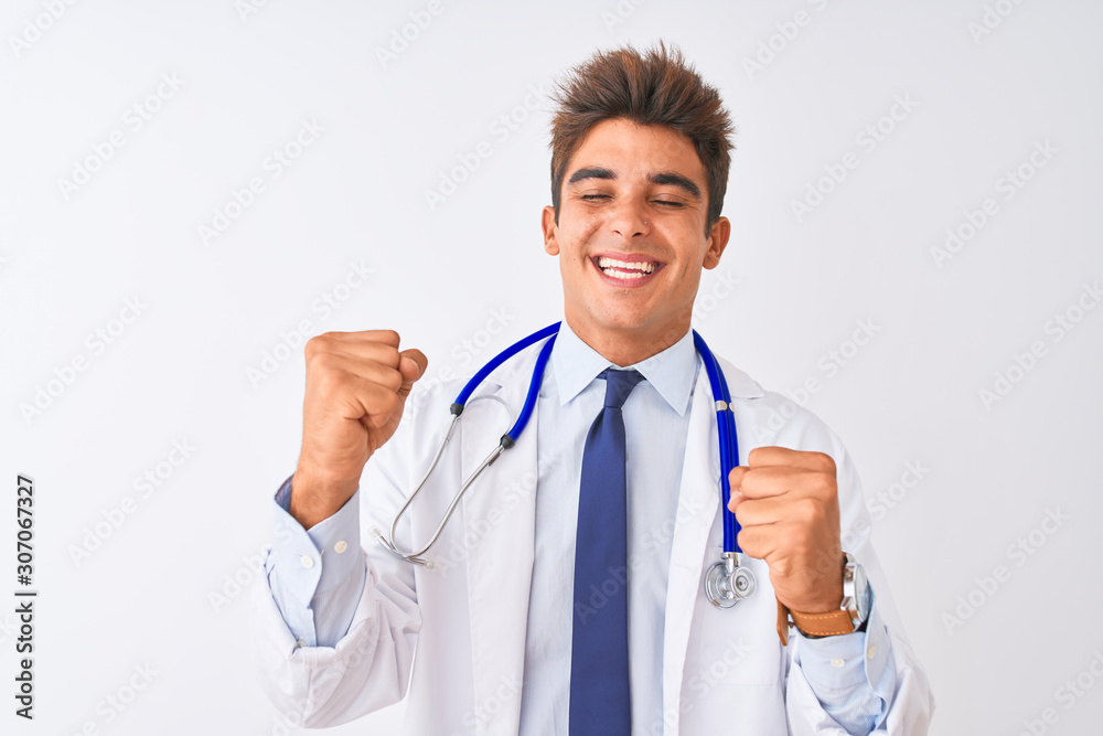 Young handsome doctor man wearing stethoscope over isolated white background very happy and excited doing winner gesture with arms raised, smiling and screaming for success. Celebration concept. Young handsome doctor man wearing stethoscope over isolated white background very happy and excited doing winner gesture with arms raised, smiling and screaming for success. Celebration concept.