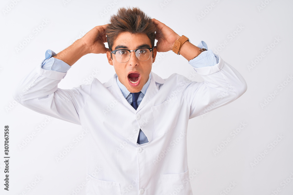 Young handsome sciencist man wearing glasses and coat over isolated white background Crazy and scared with hands on head, afraid and surprised of shock with open mouth Young handsome sciencist man wearing glasses and coat over isolated white background Crazy and scared with hands on head, afraid and surprised of shock with open mouth