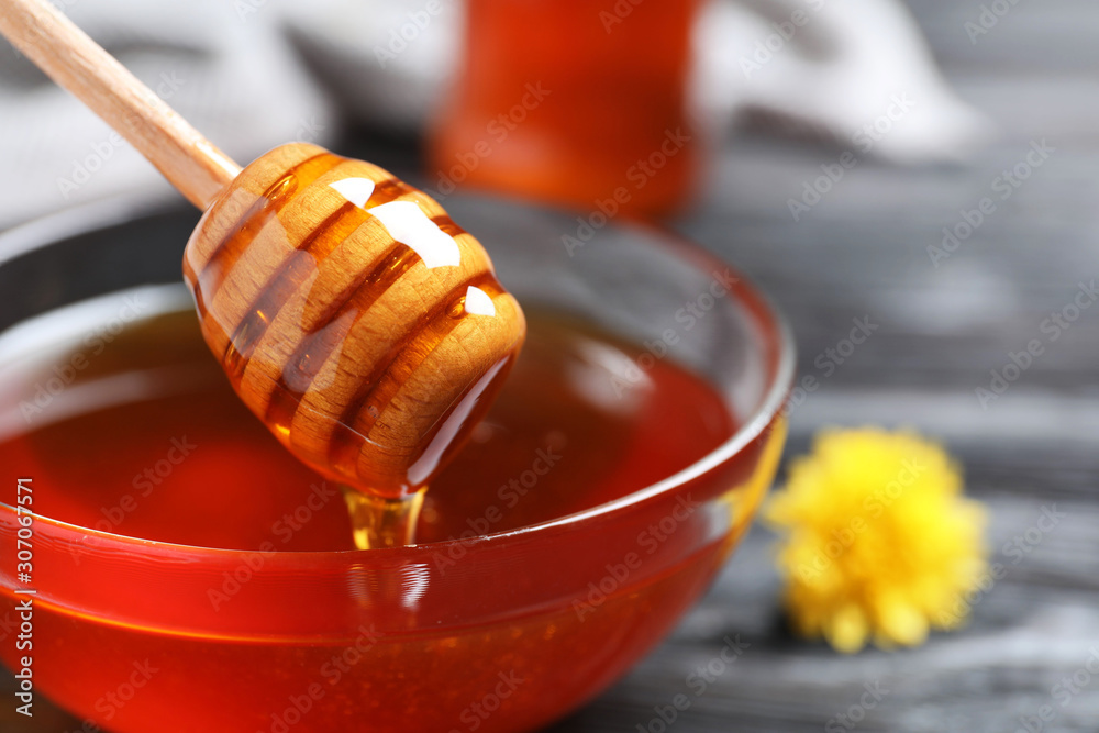Glass bowl with organic honey and dipper, closeup Glass bowl with organic honey and dipper, closeup