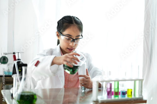 Teenage girl students learning and doing a chemical experiment and holding test tube in hands in science class on the table.Education concept