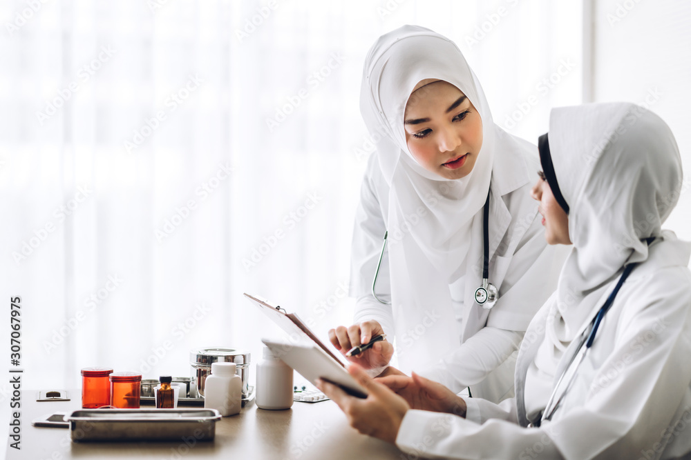 Two muslim asian female doctor working with clipboard and tablet computer on desk in hospital.healthcare and medicine Two muslim asian female doctor working with clipboard and tablet computer on desk in hospital.healthcare and medicine