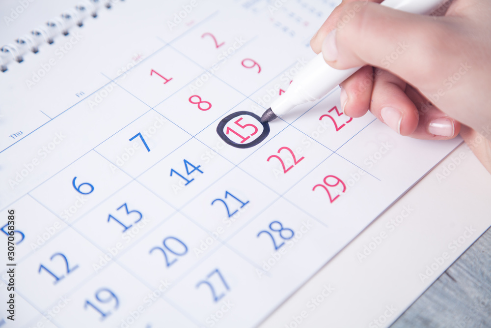 Girl hand marks calendar with a marker.