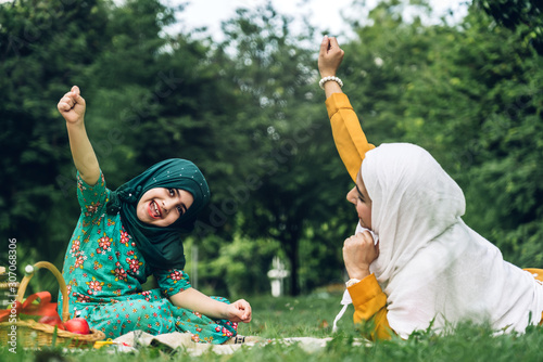 Portrait of happy muslim mother and little muslim girls child  with hijab dress smiling and enjoy relax in summer park.Education concept photo