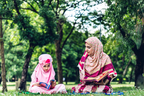 Portrait of happy muslim mother and little muslim girls child  with hijab dress smiling and enjoy relax in summer park.Education concept