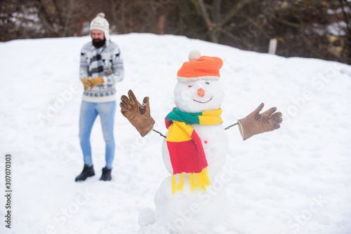 Our traditions. winter holiday outdoor. warm sweater in cold weather. man play with snow. happy hipster ready to celebrate xmas. bearded man build snowman. winter season activity. its christmas