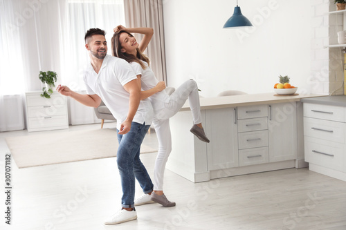 Lovely young couple dancing in kitchen at home