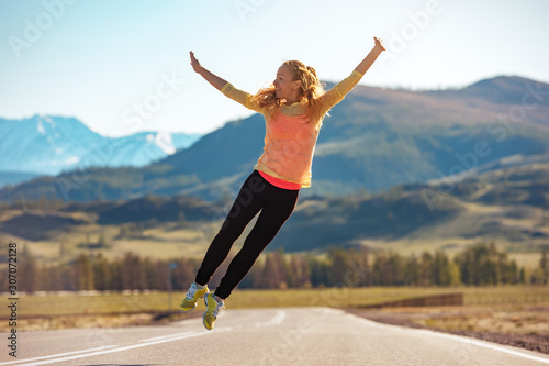 Happy sporty girl jumps on straight road