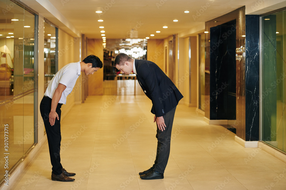 Obraz premium Multi-ethnic business colleagues bending forward to express respect and greet each other