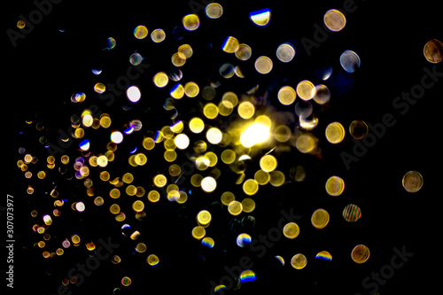 Abstract image of bokeh light at mirror of car at street road when raining or water of rain.