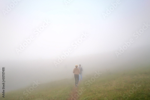 White fog cover the People or traveler walk on the Mountain hill with grass field or white clouds