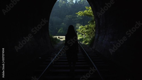 A young woman walks through a tunnel towards daylight on the railway tracks. Sri Laka. photo