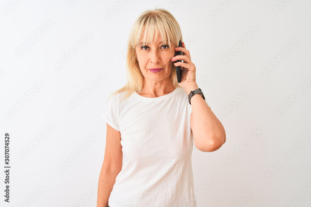 Middle age woman talking on the smartphone standing over isolated white background with a confident expression on smart face thinking serious Middle age woman talking on the smartphone standing over isolated white background with a confident expression on smart face thinking serious