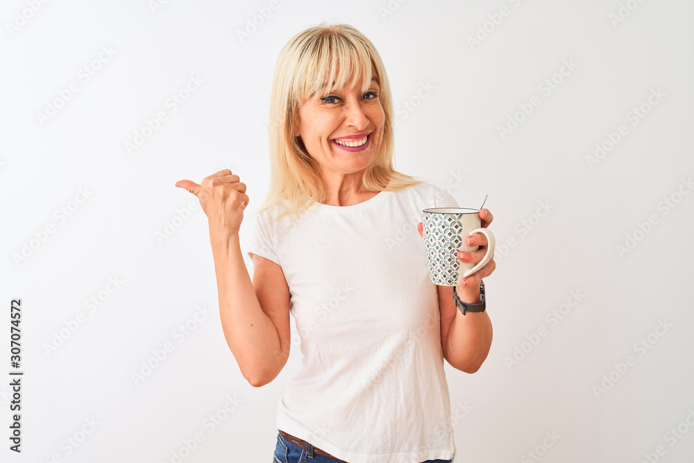 Middle age woman drinking cup of coffee standing over isolated white background pointing and showing with thumb up to the side with happy face smiling Middle age woman drinking cup of coffee standing over isolated white background pointing and showing with thumb up to the side with happy face smiling