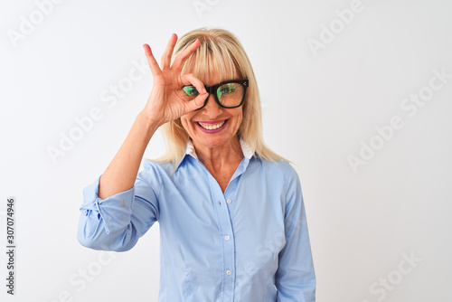 Middle age businesswoman wearing sunglasses and shirt over isolated white background with happy face smiling doing ok sign with hand on eye looking through fingers