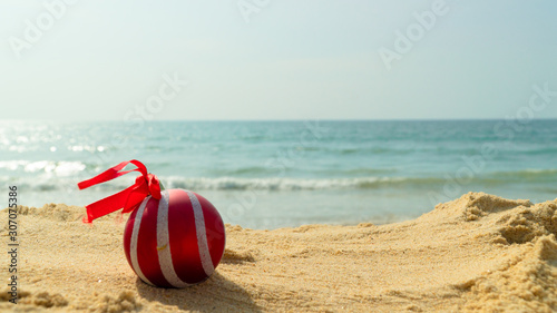 red christmas ball toy on the beach against the sea new Year