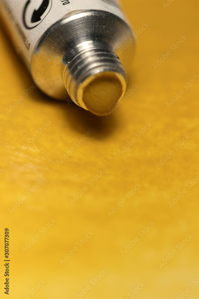 Azo Yellow Medium Watercolor paint tube and a brush on hand painted background. Azo Yellow Medium Watercolor paint tube and a brush on hand painted background.