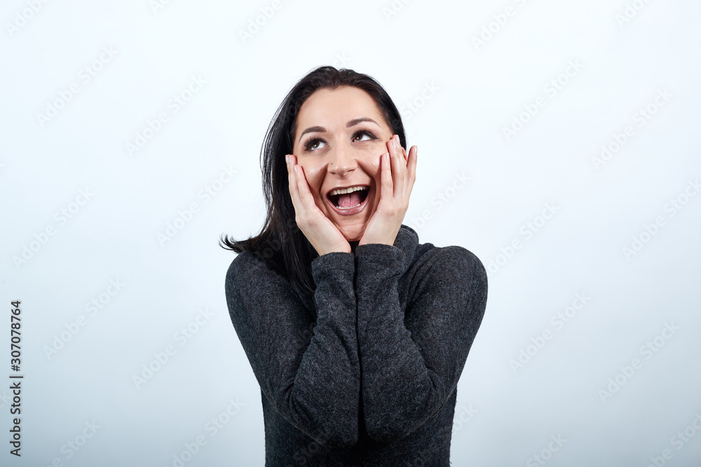 Beautiful caucasian young woman in fashion black sweater keeping hands on cheeks, screaming, announcing over isolated white background, Lifestyle concept Beautiful caucasian young woman in fashion black sweater keeping hands on cheeks, screaming, announcing over isolated white background, Lifestyle concept