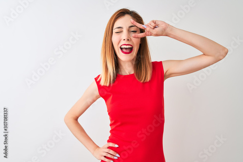 Redhead businesswoman wearing elegant red dress standing over isolated white background Doing peace symbol with fingers over face, smiling cheerful showing victory