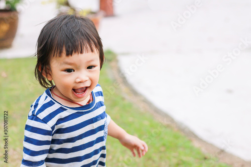 Portrait image of 1-2 years old baby. Happy Asian child girl smiling and running on the road at the park.