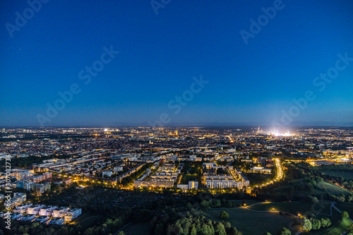 Abendlicher Panoramablick über München mti dem hell erleuchteten Oktoberfest