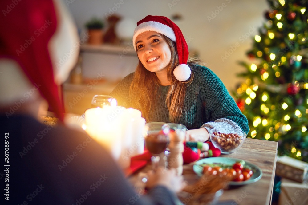 Young beautiful couple smiling happy and confident. Eating food wearing santa claus hat celebrating christmas at home Young beautiful couple smiling happy and confident. Eating food wearing santa claus hat celebrating christmas at home