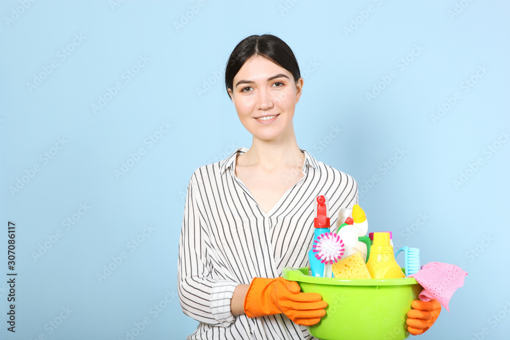 A young housewife holds in his hands cleaning products on a colored background. A young housewife holds in his hands cleaning products on a colored background.