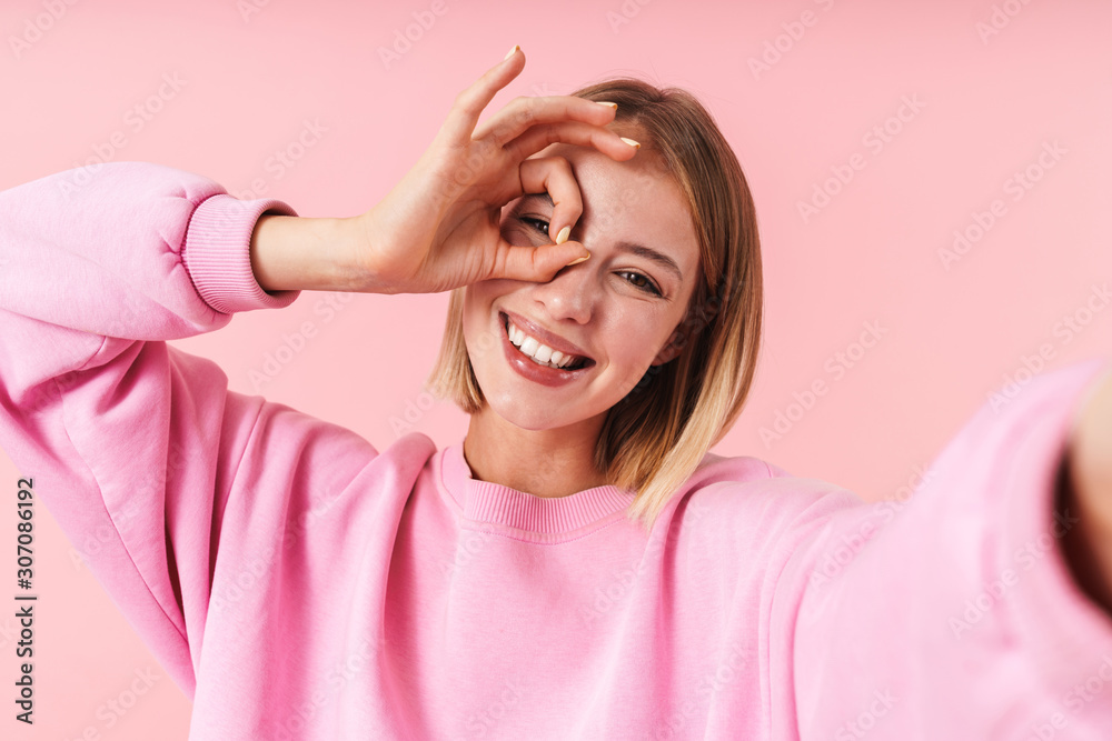 Portrait of woman smiling and showing ok sign while taking selfie photo Portrait of woman smiling and showing ok sign while taking selfie photo
