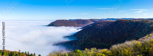 Germany, XXL panorama of beautiful aerial view above endless fog clouds in valley of swabian alb nature landscape on sunny day with blue sky near stuttgart
