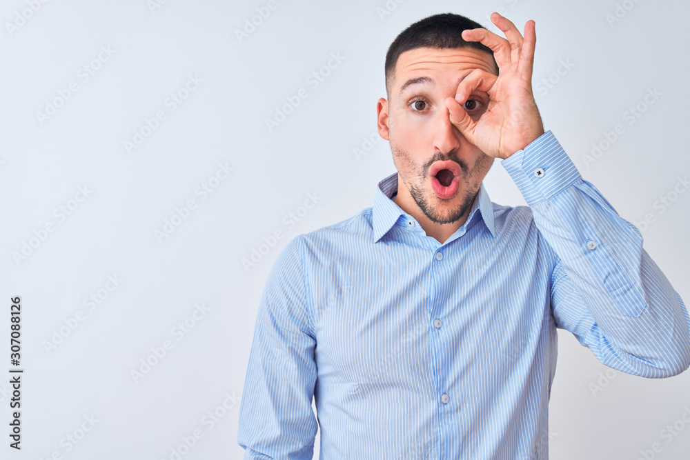 Young handsome business man standing over isolated background doing ok gesture shocked with surprised face, eye looking through fingers. Unbelieving expression. Young handsome business man standing over isolated background doing ok gesture shocked with surprised face, eye looking through fingers. Unbelieving expression.