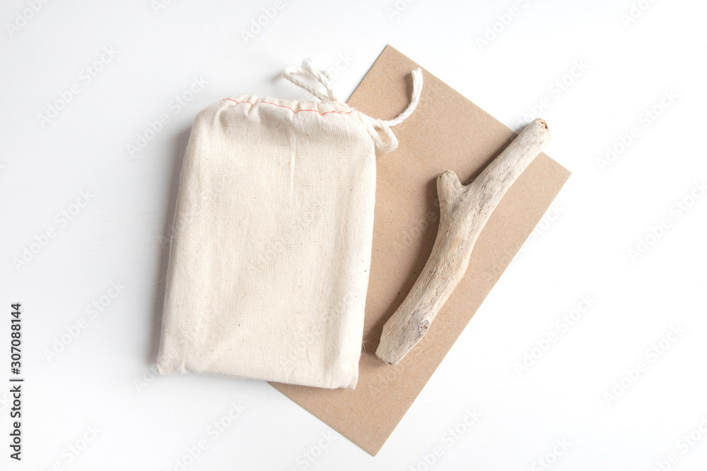 Mock up of tarot deck cotton bag with texture paper craft brown envelope and rustic stick on white background. Boho design of tarot cards pouch on white table with copy space for image or text. Mock up of tarot deck cotton bag with texture paper craft brown envelope and rustic stick on white background. Boho design of tarot cards pouch on white table with copy space for image or text.