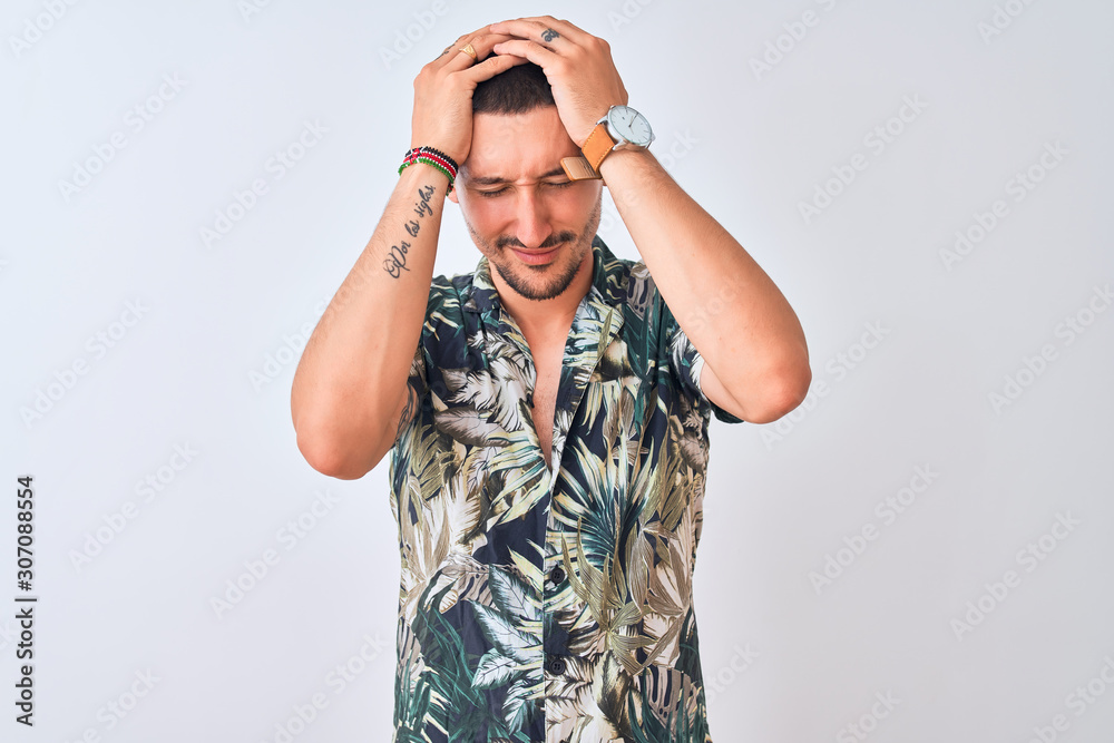 Young handsome man wearing Hawaiian summer shirt over isolated background suffering from headache desperate and stressed because pain and migraine. Hands on head. Young handsome man wearing Hawaiian summer shirt over isolated background suffering from headache desperate and stressed because pain and migraine. Hands on head.