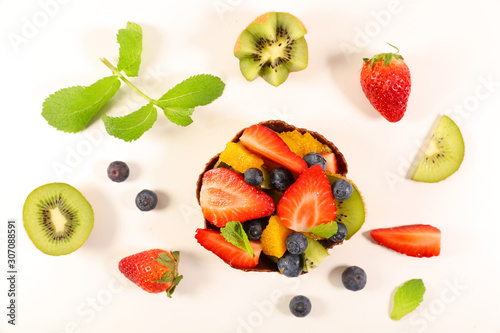 fruit salad with strawberry, blueberry, kiwi, orange and banana- top view on white background