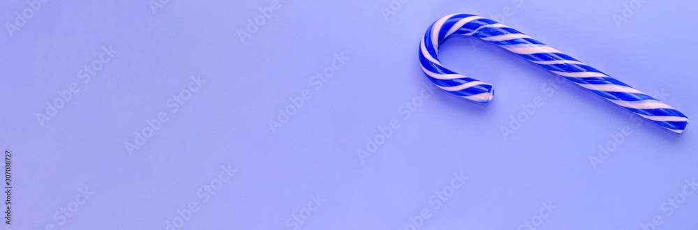 Single blue candy cane on blue background. Creative banner in minimal style. Candy Cane Day concept. Sweet Christmas symbol. Top view. Copy space Single blue candy cane on blue background. Creative banner in minimal style. Candy Cane Day concept. Sweet Christmas symbol. Top view. Copy space
