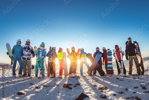 Fototapeta Big group of skiers and snowboarders at sunset mountain