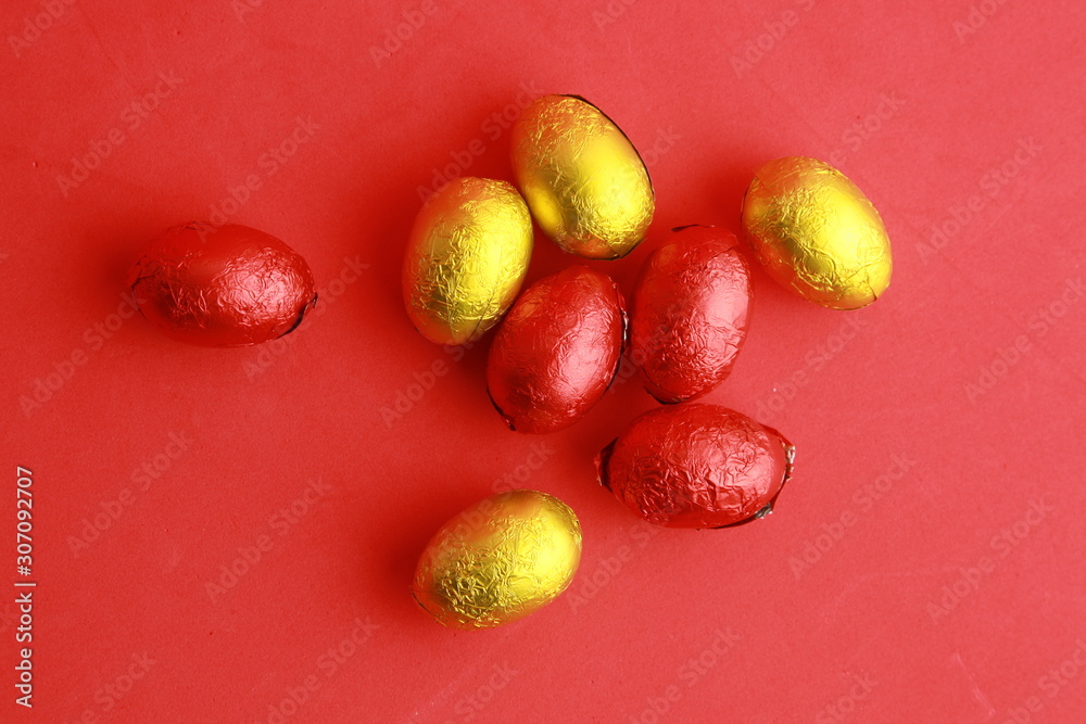 chocolate easter eggs, wrapped in yellow and red paper chocolate easter eggs, wrapped in yellow and red paper