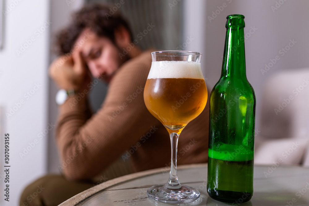 Depressed sad young addicted man feeling bad drinking beer alone at home, stressed frustrated lonely drinker alcoholic suffer from alcohol addiction having problem, alcoholism concept Depressed sad young addicted man feeling bad drinking beer alone at home, stressed frustrated lonely drinker alcoholic suffer from alcohol addiction having problem, alcoholism concept