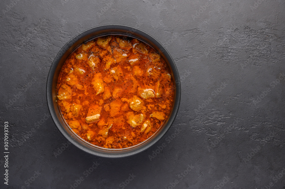 Homemade traditional Hungarian goulash dish in a saucepan against a dark background