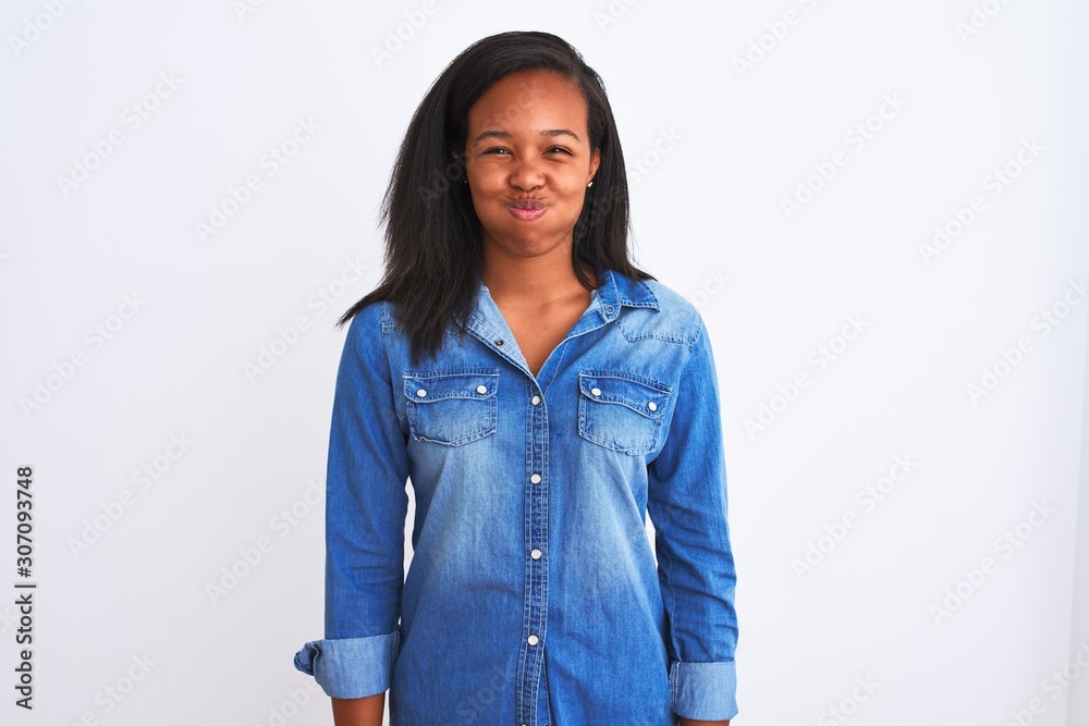 Beautiful young african american woman wearing denim jacket over isolated background puffing cheeks with funny face. Mouth inflated with air, crazy expression. Beautiful young african american woman wearing denim jacket over isolated background puffing cheeks with funny face. Mouth inflated with air, crazy expression.