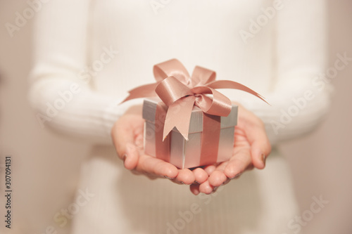 Woman hands with white sweater holding a small gift box for special event with copy space.