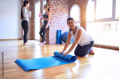 Young beautiful sportwoman using sport mat to practice yoga at gym