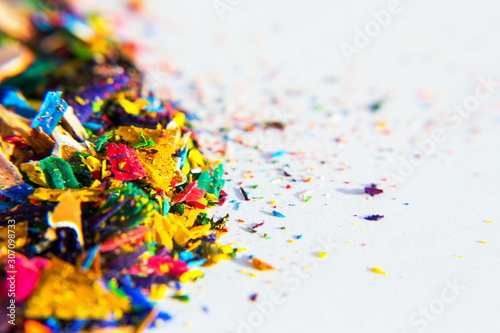 Bright colorful wooden pencil and crayon shavings on white paper background, copy space, creativity and art school concept