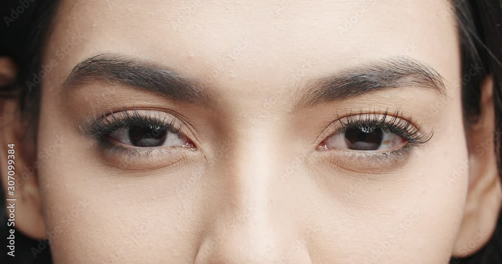 Close up shot of female eyes with makeup on eyelashes and dark brown irises looking around, isolated on black background 4k footage Close up shot of female eyes with makeup on eyelashes and dark brown irises looking around, isolated on black background 4k footage