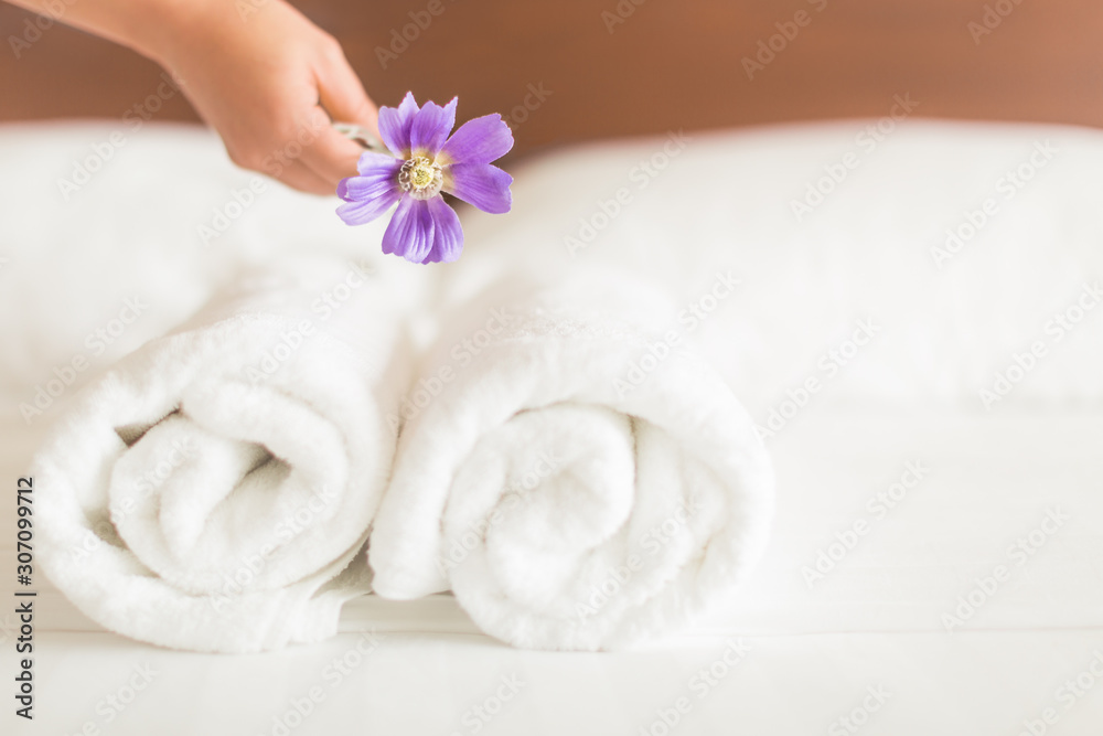 A woman cleaning the hotel bed, with clean white towels and a flower decoration. A woman cleaning the hotel bed, with clean white towels and a flower decoration.