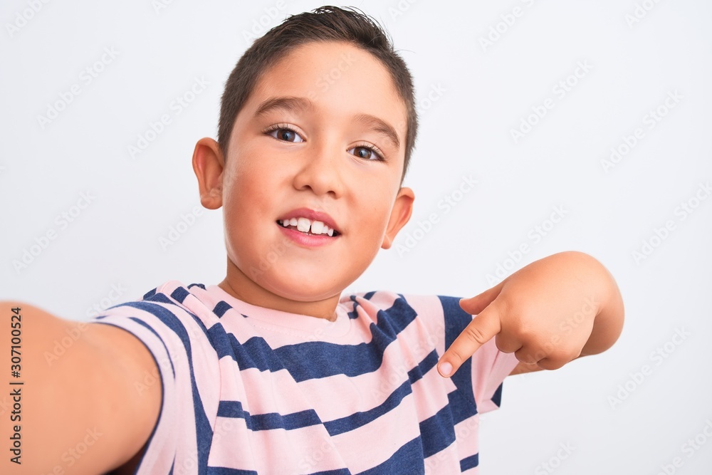 Beautiful kid boy wearing casual striped t-shirt make selfie over isolated white background with surprise face pointing finger to himself Beautiful kid boy wearing casual striped t-shirt make selfie over isolated white background with surprise face pointing finger to himself