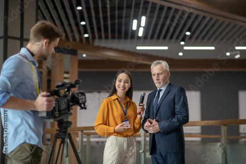 Reporters with videocamera having interview with famous businessman photo