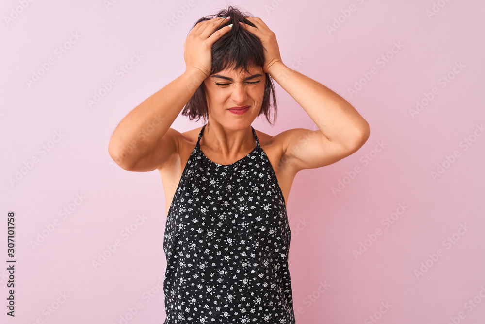 Young beautiful woman wearing black floral dress standing over isolated pink background suffering from headache desperate and stressed because pain and migraine. Hands on head. Young beautiful woman wearing black floral dress standing over isolated pink background suffering from headache desperate and stressed because pain and migraine. Hands on head.