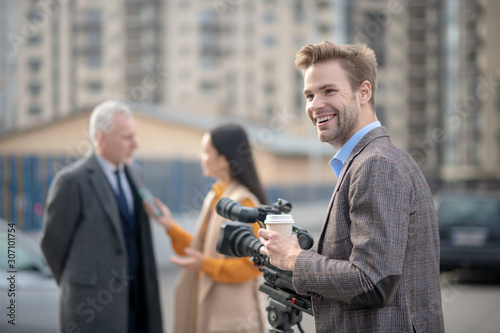 Young reporter with coffee in his hand smiling
