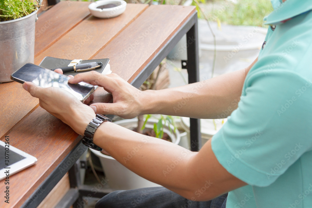 man using mobile phone on wooden table