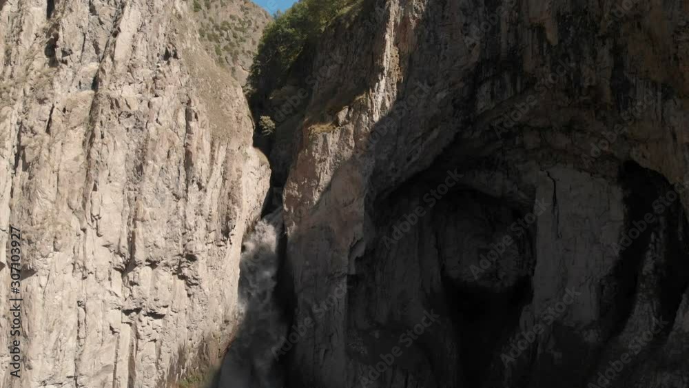 Aerial view of a huge waterfall from a sheer cliff in the Caucasus. Close shot of a large stream of water in the mountains. Caucasian Iceland